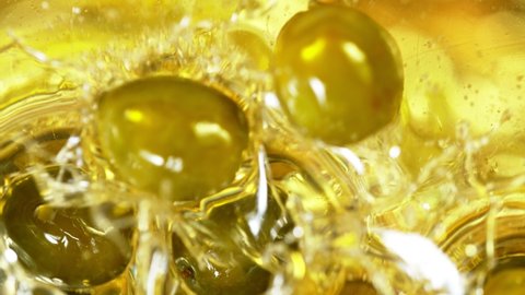 Super Slow Motion Shot of Fresh Green Olives Splashing into Olive Oil at 1000 fps.