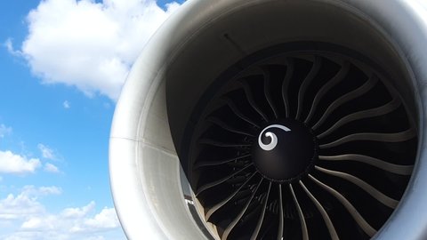 Jet turbine engine of aircraft rotating by wind with clouds and blue sky background.Aviation industry affected by covid-19 pandemic aircraft had to stop all flight plan.