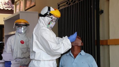 Pekalongan , Central Java , Indonesia - 11 28 2020: doctor in a protective suit taking a nasal swab from a person to test for possible coronavirus infection, Pekalongan, Indonesia, November 19, 2020
