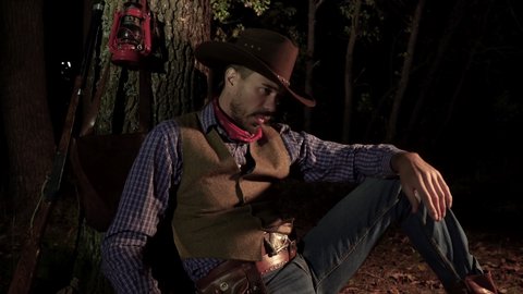 Cowboy with a handgun in the forest at night. Life in the wild west of America. 4K