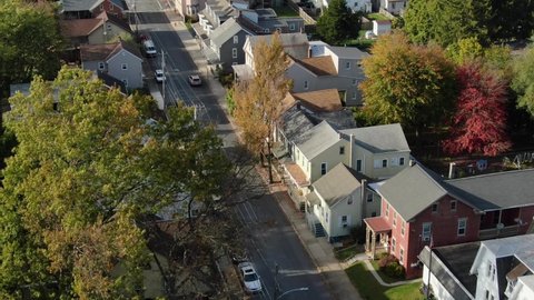 Aerial tilt up reveals two story homes in small town community neighborhood. Cars on quiet street. Establishing shot in Northeast United States of America, USA.