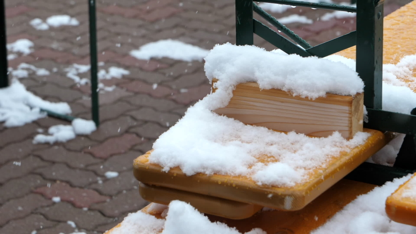 Snow piling up on ski resort bench during snowfall. Static, slomo, high angle