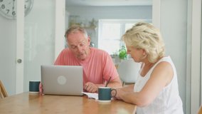 Retired senior couple at home in kitchen using laptop to shop online or check personal finances - shot in slow motion - Powered by Shutterstock - Get 15% off with code: PIKWIZARD15