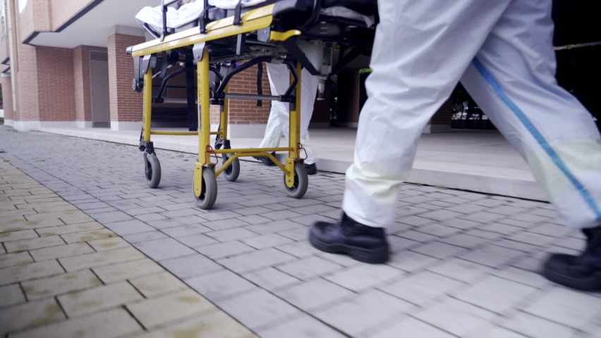 Emergency doctor and nurse or paramedics dressed in personal protective equipment ppe transport a patient on a wheeled stretcher during coronavirus covid-19 pandemic
 Royalty-Free Stock Footage #1063294537