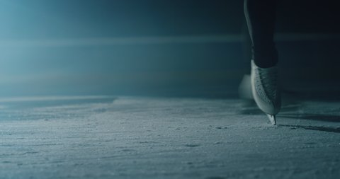 Cinematic close up shot of female figure skater's skating shoes while performing a woman's single choreography on ice rink during a competition. Concept of perfection, precision, freedom, passion.