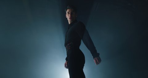 Cinematic shot of young male artistic figure skater is performing a man's single skating choreography on ice rink before start of a competition. Concept of perfection, precision, freedom, passion.