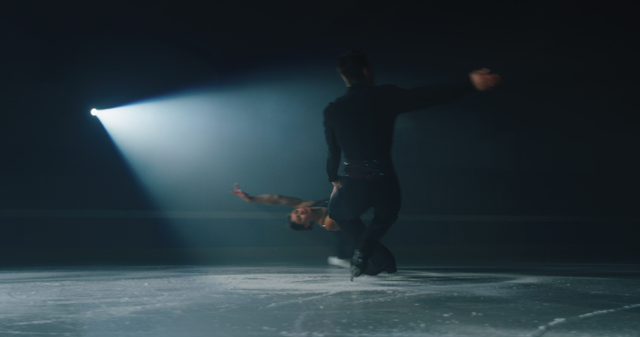 Cinematic shot of young couple of artistic figure skaters is performing a pair skating choreography on ice rink before start of a competition. Concept of perfection, precision, freedom, passion. Royalty-Free Stock Footage #1063296172