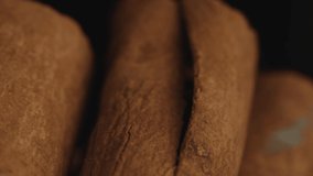 Cinnamon sticks on a dark background.  Spicy cinnamon seasoning for baked goods, fruit desserts, puddings and drinks. Extreme close-up, macro view. Spinning. 4K video