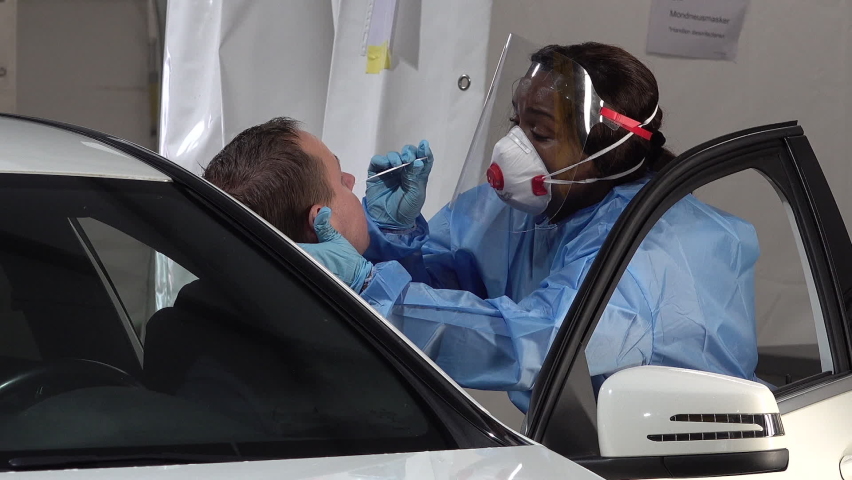 ROTTERDAM, NETHERLANDS – OCTOBER 2020: Nurse wearing protective medical equipment (including face mask and shield) takes nose swab from possible coronavirus patient in mobile Covid-19 test facility  | Shutterstock HD Video #1063298662
