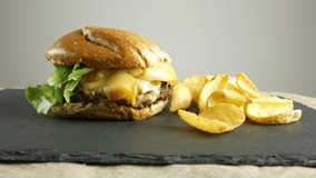 Gourmet burger with fried potatoes in their skins on slate plate, burger chef menu on black background