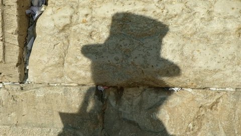 A single Orthodox Jew praying in front of the Wailing wall (Western wall), by the afternoon light, leaving a significant shadow upon the Holy stones, May 30th, 2018, East Jerusalem, Israel.