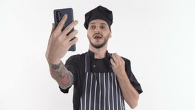 Chef in uniform doing video call or online class on smartphone holding it in hand