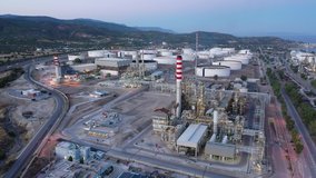 Aerial drone video of famous full working plant and oil - gas refinery in Corinth area at dusk, Agioi Theodoroi, Greece