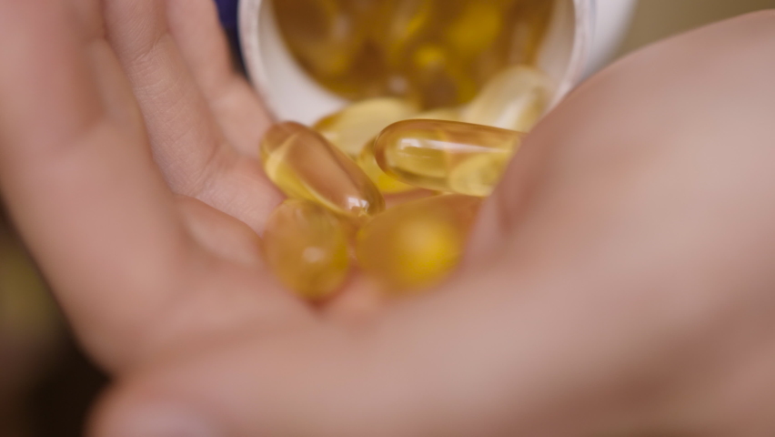 Omega 3 Gold Fish Oil Capsules. Natural Medicine, Sport, Healthy Lifestyle, Supplements, Dietary, Nutrition, Weight Loss, vitamin D. Man Pouring Fish Oil Capsules to Hand, Close up. Omega3 closeup. Royalty-Free Stock Footage #1063307320