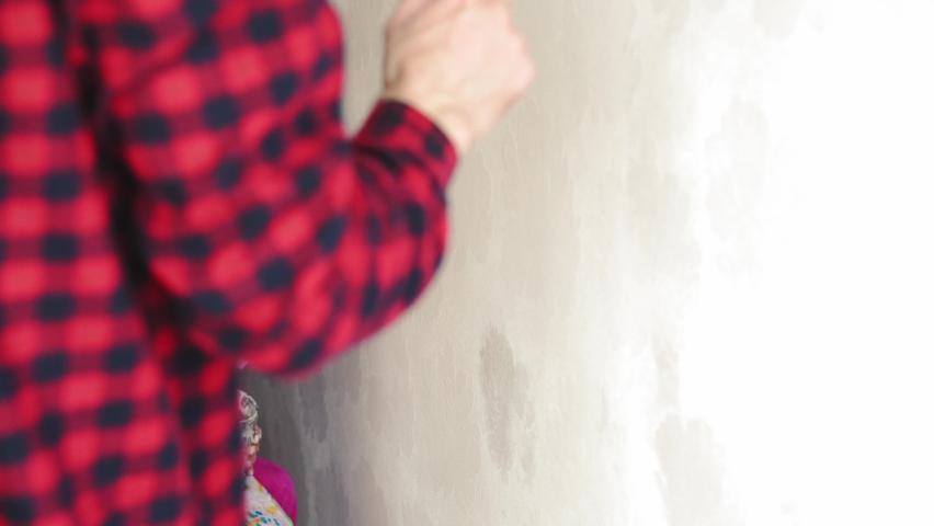 Repair, renovation, home, family, childhood, parenthood, fatherhood, self-isolation, quarantine concept - close-up little 3 years old girl playing with roller, painting wall in apartment white paint.