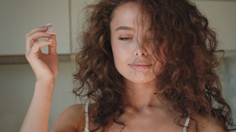 A young woman is spreading her curly hair and looking at the camera. 4K