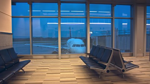 Generic Airport Interior at Empty Terminal Gate Departure Lounge Area with No People and a Parked Jet Airliner seen through the Windows