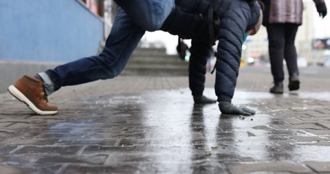 Minsk, Belarus - 30 July 2020: Man in winter dress slip on sidewalk with ice closeup. illustrtive editorial