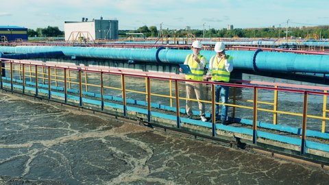 Two male specialists having a discussion at a wastewater treatment plant