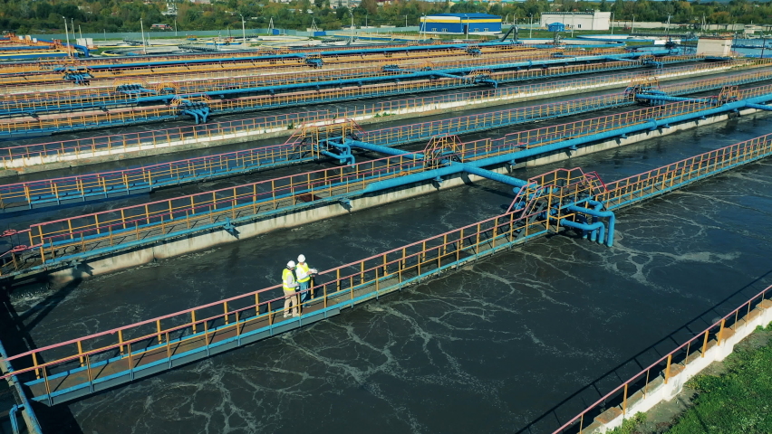 Two male specialists inspecting a modern wastewater treatment plant