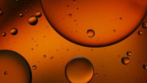 Dark gold color of oil drop floating on the water. Orange background of oil drop.