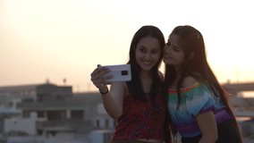 Two beautiful girls taking a selfie with smartphone. LGBT Pride Month, Gay Pride Symbol. Happy lesbian couple taking picture on smartphone. Beautiful Asian girls taking selfie posing outdoors.