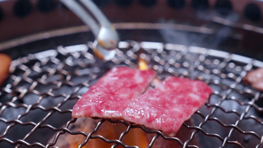 4K UHD Slow motion Handheld : Charcoal grilled Kobe Wagyu beef sliced Yakiniku , gourmet Japanese-style bbq.
