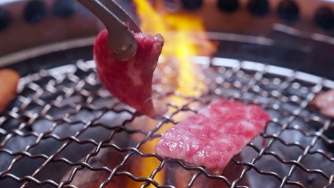 4K UHD Slow motion Handheld : Charcoal grilled Kobe Wagyu beef sliced Yakiniku , gourmet Japanese-style bbq.