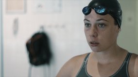Young student put her swimming goggles on and prepare to start training in indoor swimming pool. Slow motion video.
