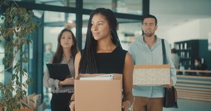 Young business people of mixed-races with boxes come back to office. Colleagues going to work in modern workspace, teamwork together. 4k Slow motion video.
