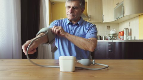 An aged man measuring the blood pressure at home