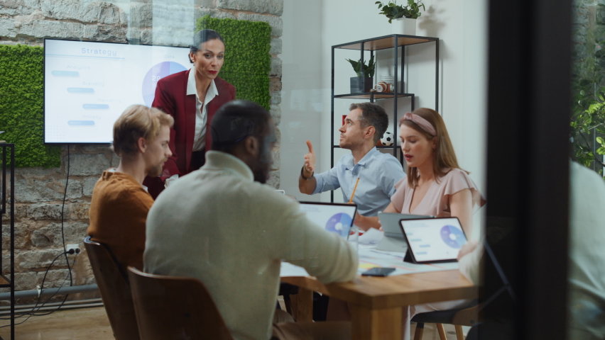 Office Conference Room Meeting: Female Chief Executive Talking to a Diverse Team of Professional Businesspeople. Creative People Listen to CEO Discuss Design, Data Analysis, Plan Marketing Strategy