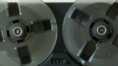 Black reel to reel tape recorder. Rotating retro tape. Vintage music player close up. Spinning reels transparent. Counter counts down record. 