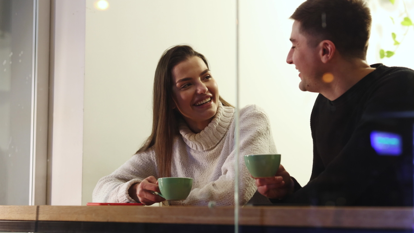 Young couple sitting in modern cafe on date. Caucasian girl and guy talk to each other. Love at first sight like conversation. Flirting guy with pretty girl in cafe ask on romantic date Royalty-Free Stock Footage #1063361284
