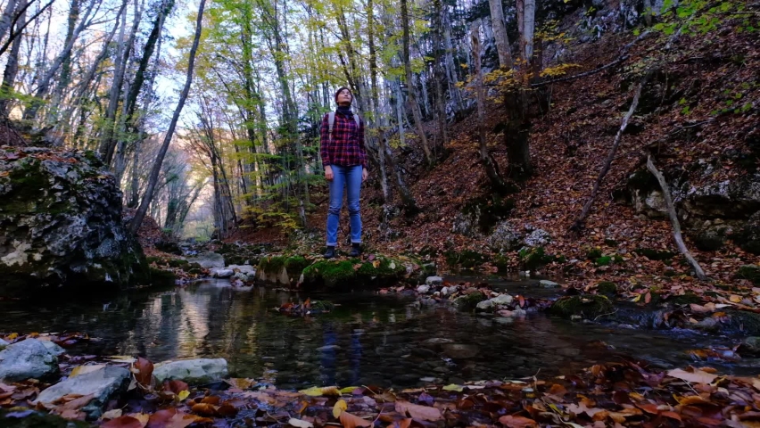 A young Asian woman enjoys the autumn forest and pond