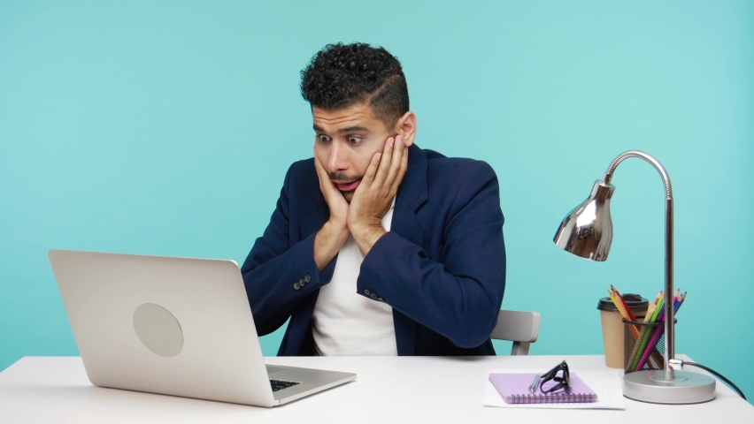 Oh my god! Excited shocked businessman surprised with information he see on laptop sitting in office, astonishment. Indoor studio shot isolated on blue background | Shutterstock HD Video #1063362796