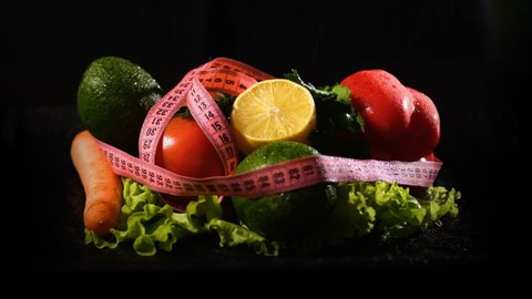 Spraying Fresh Vegetables Wrapped in Measuring Tape by the Black Background. Slow Motion. Healthy Lifestyle, Vegetarian Food and Dieting Concept