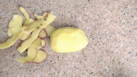 Peeling raw potato with knife according to step-by-step recipe for vegetable dish for educational and entertaining cooking blog, top view, time lapse.