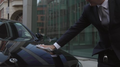 London , United Kingdom (UK) - 09 30 2020: Chauffeur polishes hood of car. Slow-motion