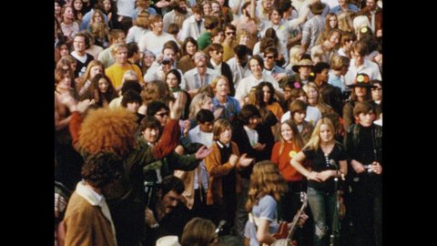 1970s: Rock band performs before crowd in Griffith Park, Los Angeles, reaching crescendo as audience members clap and dance.