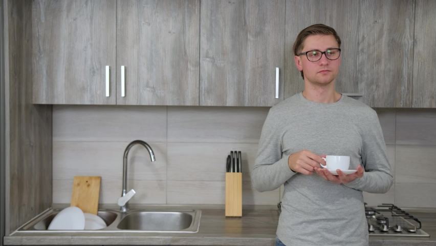 Guy is drinking hot strong coffee from a white cup while take a break from work. Caucasian man drinks morning coffee in the kitchen.