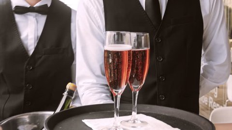 4k medium steadicam video of waiter and champagne glasses on a tray, walking to a customer in hotel or restaurant. 