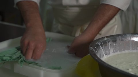 Enterprise, factory, farm for production of dairy cheese products. A cook in a white coat, clothes, fills milk buratta with stracciella cheese with his hands, ties the bag with a knot of plastic tape