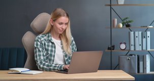 Young Woman Freelancer working on her Laptop from Home Office. Young Female is surfing, browsing, looking at the Screen, typing, scrolling. Studying, Working Indoor, Online Distantly Job, Work.