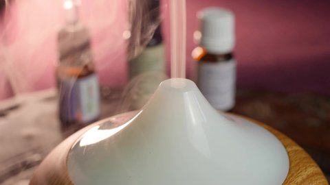Essential oil diffuser working, close up of smoke and smooth background with bottles. Spa, aromatherapy