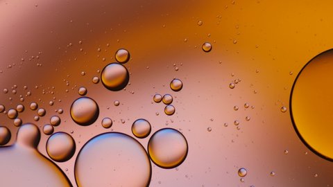 Dark gold color of oil drop floating on the water. Orange background of oil drop. The art of water surface for your products display and artwork design with copy space.