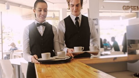 4k wide steadicam video of waiter and coffee on a tray, walking to a customer in hotel or restaurant cafe. 
