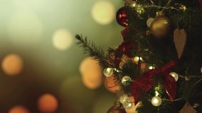 New Years Christmas festive background with lights on the background. Christmas tree. Decorations, red gold balls and glowing bulbs on the tree. Warm home mood. Depth of field. Spinning. 4K video