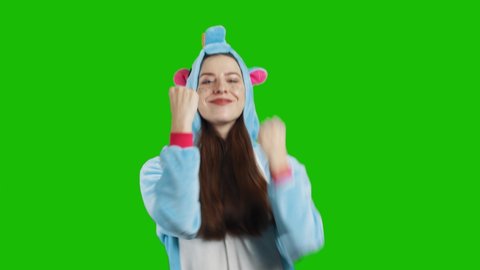 Portrait of a cute young brunette girl in a beautiful unicorn costume on chrome key green background. Smiling, dancing and playing. Animator in costume. Unicorn pajamas. 4K video with alpha matte