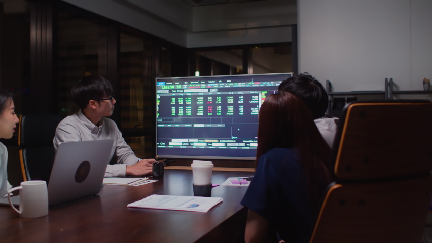 Young Asian businessman lead group of business financial team in strategic meeting presentation, work late night in office. Marketing strategy analysis, stock market trading, or corporate teamwork | Shutterstock HD Video #1063384678